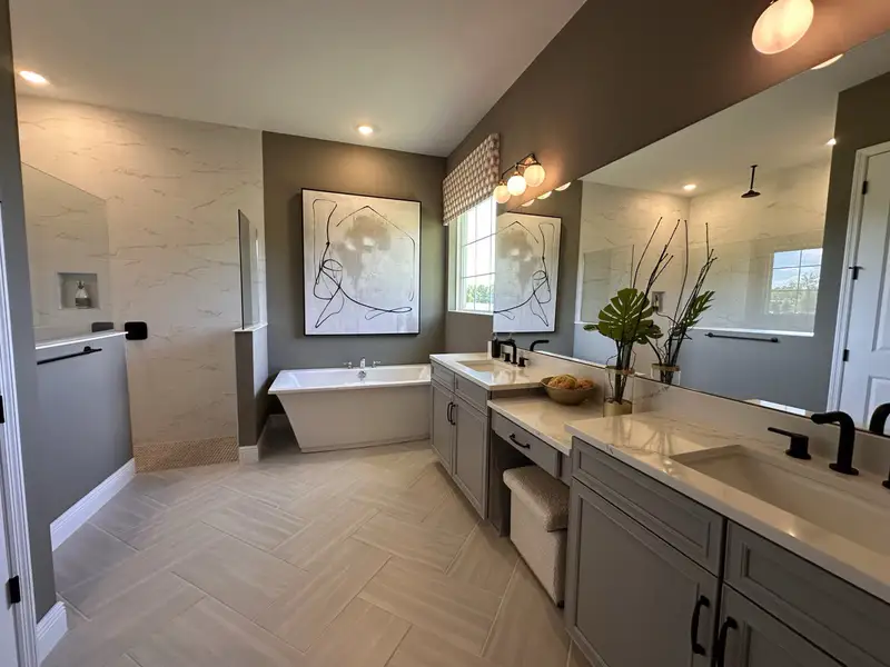 Elegant bathroom with a freestanding tub, double vanity, abstract art, and modern fixtures.