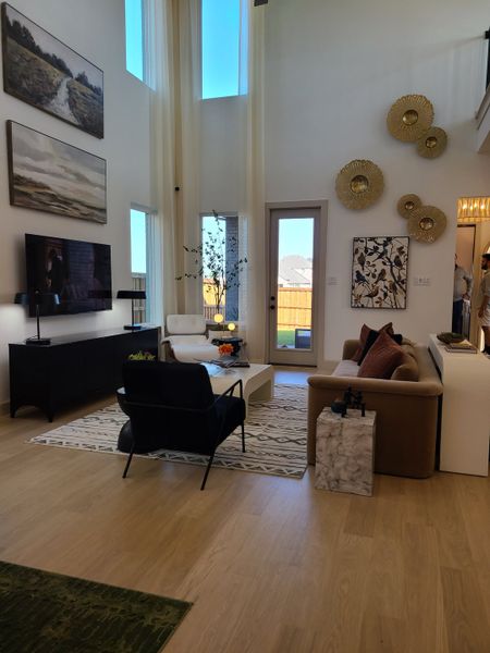 A spacious living room with high ceilings, modern art, and elegant decor, featuring natural light and cozy seating.