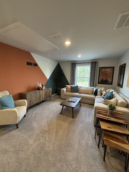 A cozy living room with colorful accent wall, modern furniture, and natural light filtering through the window.