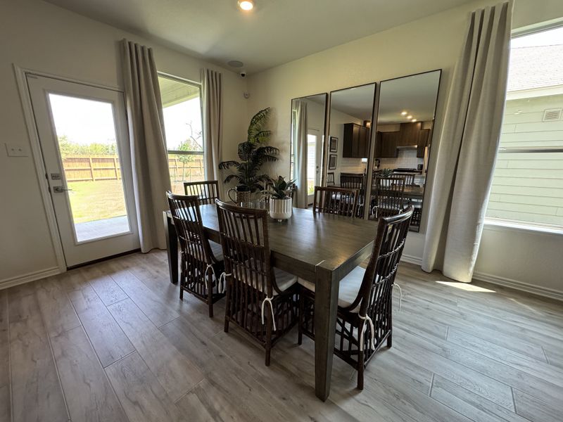 A bright dining area with large windows, elegant drapes, and a wooden table set in a modern open-concept space. A bright dining area with large windows, elegant drapes, and a wooden table set in a modern open-concept space.