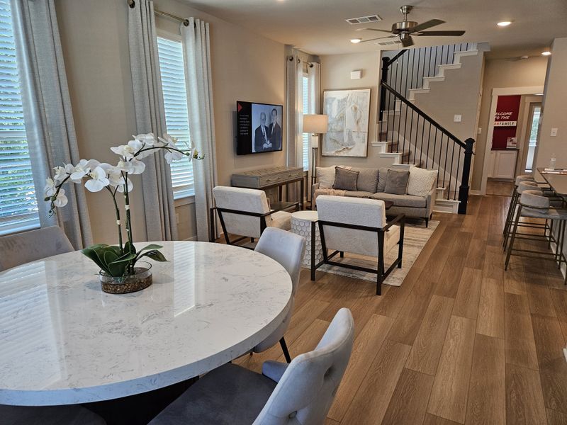 An inviting living area with wood flooring, cozy seating, and a chic dining table with an elegant orchid centerpiece. An inviting living area with wood flooring, cozy seating, and a chic dining table with an elegant orchid centerpiece.