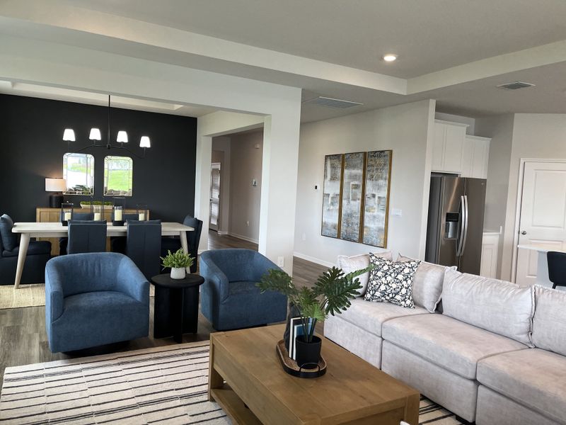 A modern open-concept living and dining area with plush seating, stylish decor, and sleek lighting fixtures.