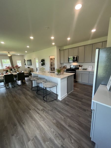 An elegant open-concept kitchen with sleek gray cabinets, a breakfast bar, and warm wooden floors.