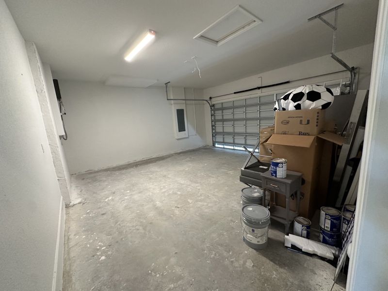 A spacious garage with ample storage space, featuring a large door and modern lighting.