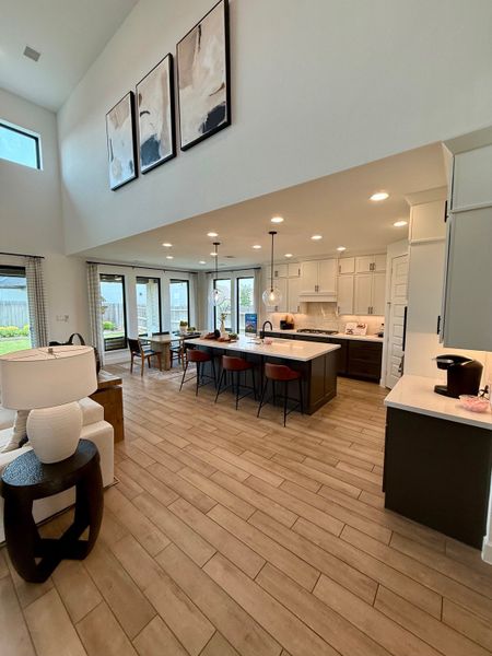 A bright, open-concept living area featuring wood floors, a modern kitchen with an island, and elegant wall art.
