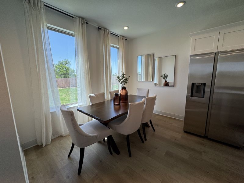 A bright dining area with elegant white chairs, a dark wood table, and natural light from large windows. A bright dining area with elegant white chairs, a dark wood table, and natural light from large windows.
