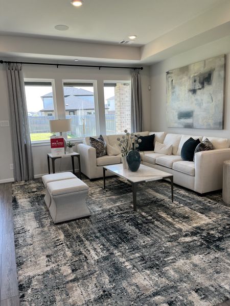 A cozy living room featuring a plush white sofa, abstract art, and large windows overlooking a fenced backyard.