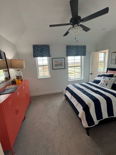 A cozy bedroom with striped bedding, vibrant red storage, and geometric-patterned curtains, accented by a sleek ceiling fan. A cozy bedroom with striped bedding, vibrant red storage, and geometric-patterned curtains, accented by a sleek ceiling fan.