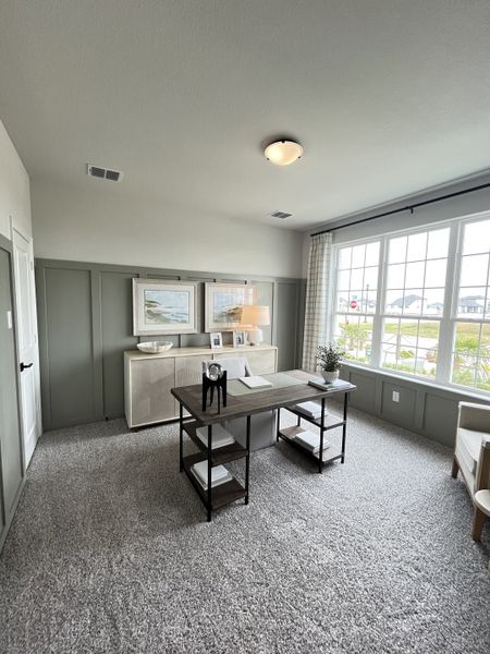 A bright, elegant home office with a large window, neutral decor, and sleek furnishings for a productive workspace.