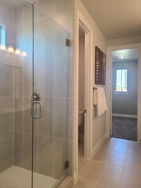 A modern bathroom featuring a sleek glass shower, neutral tiles, and elegant lighting.