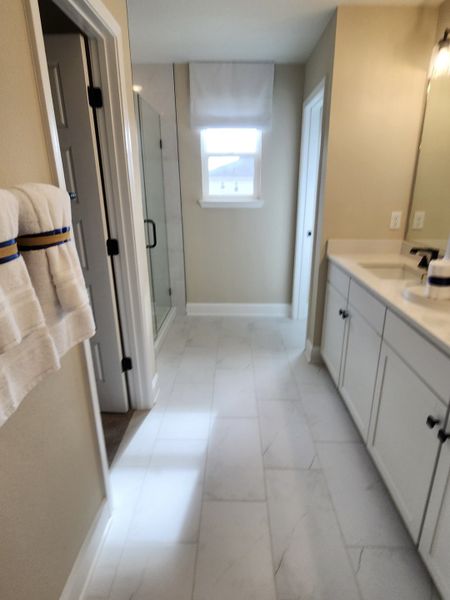 A modern bathroom featuring white cabinetry, sleek countertops, and a glass shower with elegant fixtures.