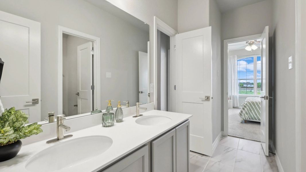 Luxurious double vanity with sleek fixtures and marble flooring in Hulen Trails. Luxurious double vanity with sleek fixtures and marble flooring in Hulen Trails.