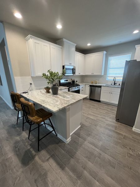 A modern kitchen with white cabinets, granite counters, and stainless appliances. A modern kitchen with white cabinets, granite counters, and stainless appliances.
