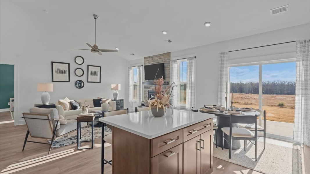 Open concept living spaces with large family room with fireplace and adjacent wood cabinetry kitchen in Greenville, SC