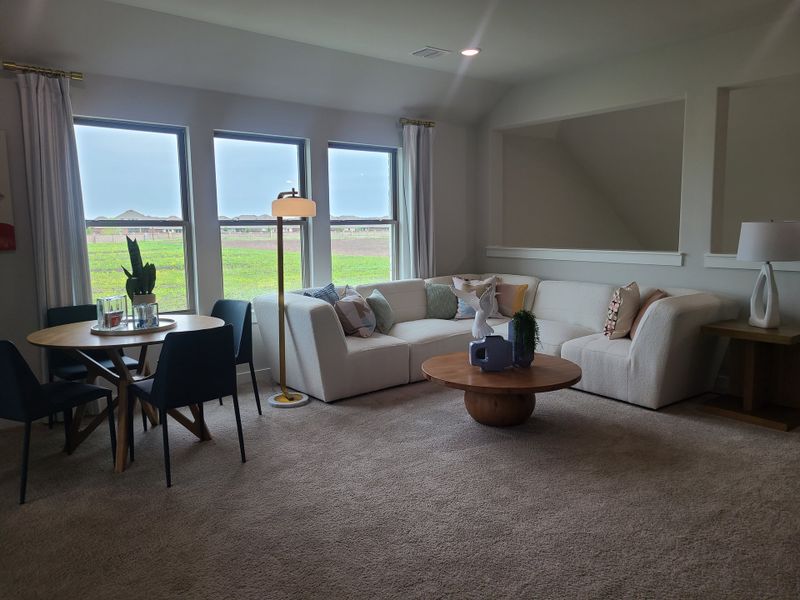A cozy living room with a plush sectional, round wood coffee table, and a dining area by large windows with scenic views.