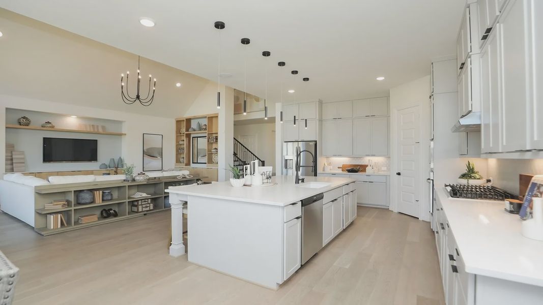 Luxurious kitchen features elegant white cabinetry, expansive island, and sleek pendant lighting in Brookewater. Luxurious kitchen features elegant white cabinetry, expansive island, and sleek pendant lighting in Brookewater.