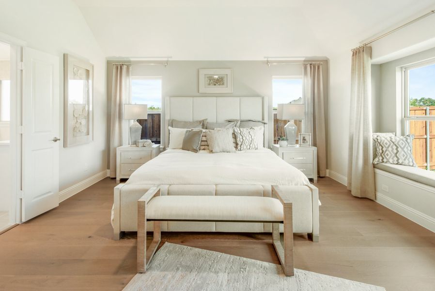 Master bedroom with white upholstered bed, hardwood floors, window seat, and neutral decor