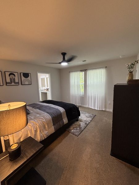 A cozy bedroom featuring soft carpet, a sleek ceiling fan, and modern artwork for a stylish and inviting atmosphere. A cozy bedroom featuring soft carpet, a sleek ceiling fan, and modern artwork for a stylish and inviting atmosphere.
