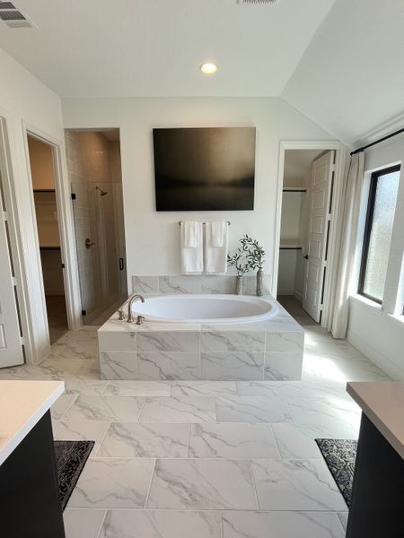 A luxurious bathroom featuring a marble-tiled bathtub, elegant artwork, and soft natural lighting. A luxurious bathroom featuring a marble-tiled bathtub, elegant artwork, and soft natural lighting.