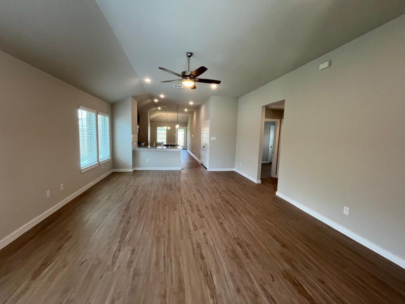 An open, airy living space with wood flooring, ceiling fan, and large windows welcoming natural light.
