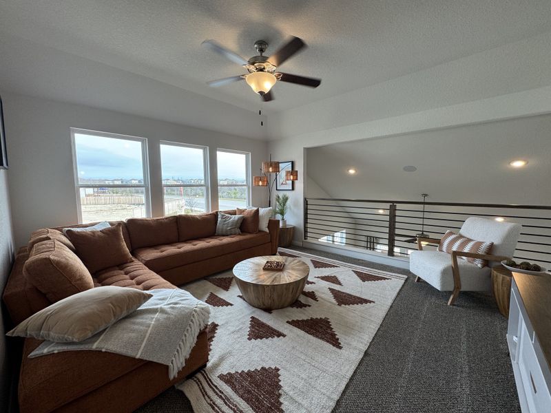 A cozy loft with a sectional sofa, patterned rug, and modern lighting, perfect for relaxation.