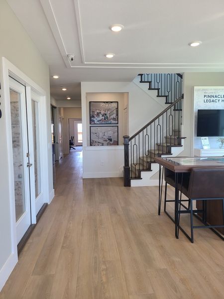 A bright entryway with light wood floors, a modern staircase, and stylish décor.