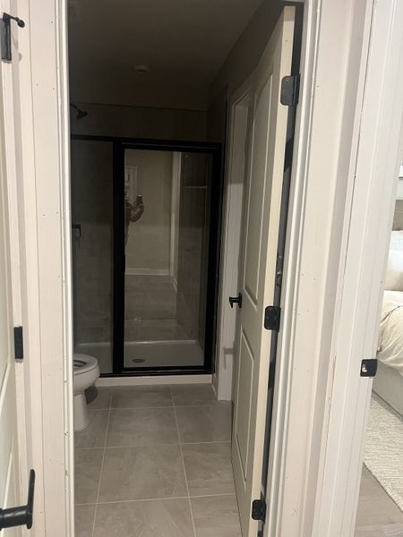 A modern bathroom with light tiles, a sleek glass shower door, and elegant black accents.