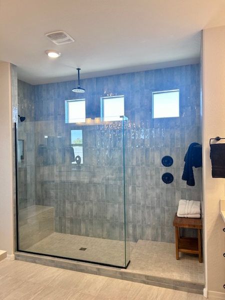 A spacious shower with elegant tilework, rain showerhead, and clear glass enclosure. A spacious shower with elegant tilework, rain showerhead, and clear glass enclosure.