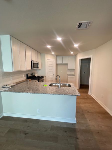 A contemporary kitchen featuring granite countertops, sleek appliances, and wood flooring, offering a modern culinary space.