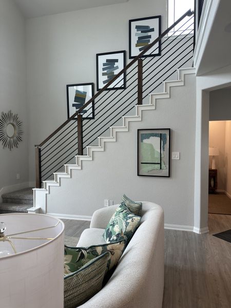 A modern living area with a sleek staircase, abstract art, and cozy seating, showcasing stylish decor and neutral tones.
