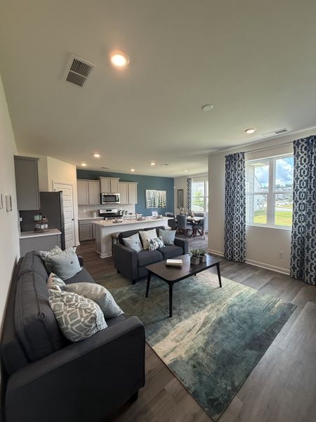 An inviting open-concept living room with modern furnishings, hardwood floors, and abundant natural light.