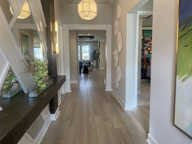 A modern hallway with elegant lighting, abstract art, and sleek wood flooring, leading to a bright living area. A modern hallway with elegant lighting, abstract art, and sleek wood flooring, leading to a bright living area.
