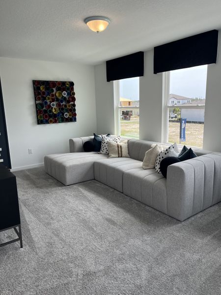 A cozy living room with a modern gray sectional sofa, colorful wall art, and plush carpet. A cozy living room with a modern gray sectional sofa, colorful wall art, and plush carpet.