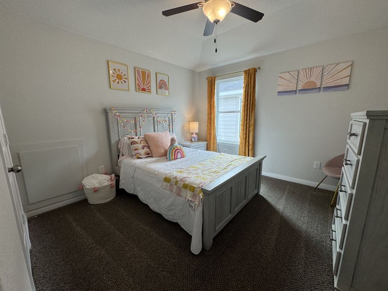 A cozy bedroom featuring a textured bedframe, colorful art, cheerful decor, and warm lighting for a welcoming ambiance.