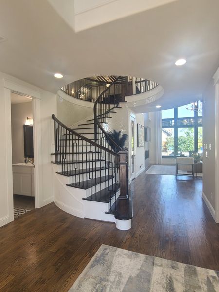 A grand entryway with a sweeping staircase, elegant wood floors, and bright natural lighting for a welcoming atmosphere.
