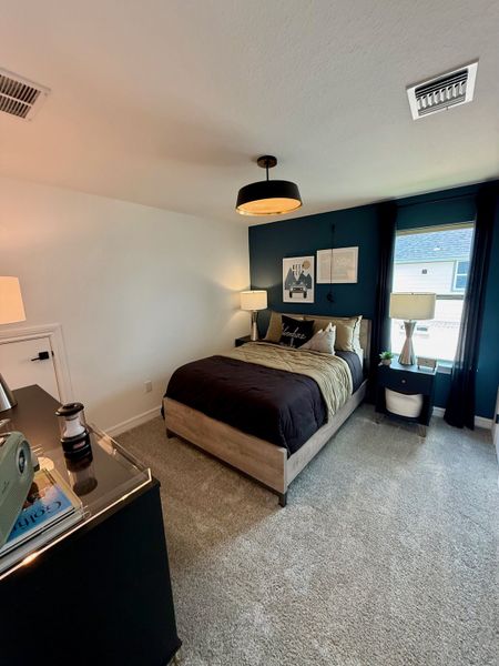 A cozy bedroom with dark accents, stylish lighting, and plush carpeting for a modern and inviting atmosphere.