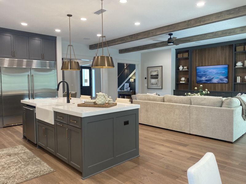 A modern open-concept living area with a sleek kitchen island, elegant lighting, and wood accents.