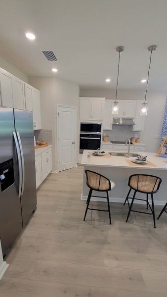 A modern kitchen with sleek white cabinets, stainless steel appliances, and a stylish island with pendant lighting. A modern kitchen with sleek white cabinets, stainless steel appliances, and a stylish island with pendant lighting.