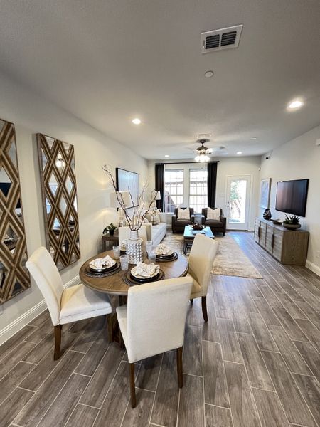 A cozy dining and living area with elegant decor, featuring a stylish round table, cream chairs, and wood tile flooring. A cozy dining and living area with elegant decor, featuring a stylish round table, cream chairs, and wood tile flooring.