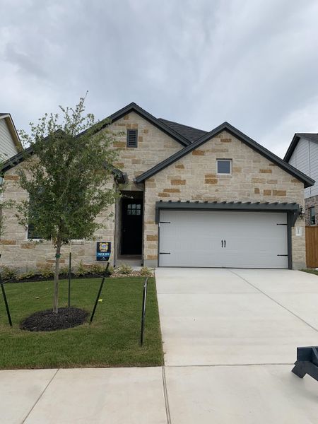 Charming stone-brick home with a lush lawn in Cedar Brook by M/I Homes, Leander, TX.