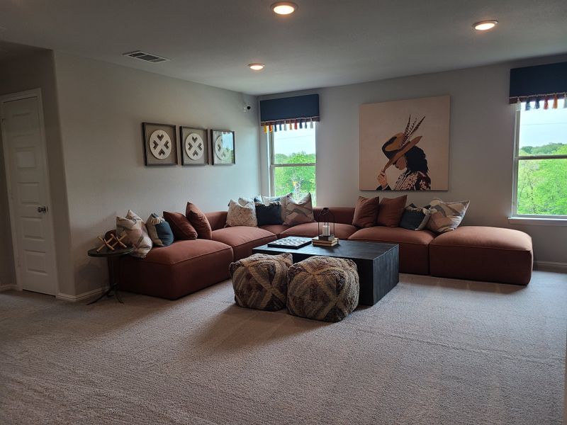 A cozy living room featuring a sleek sectional sofa, modern artwork, and natural light through large windows.