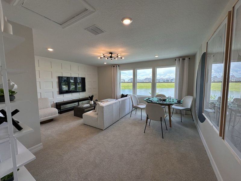 A modern living room with a chic sectional, stylish paneling, and large windows overlooking a scenic landscape.