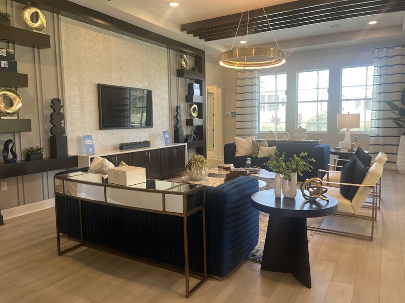 A modern living room with chic navy seating, elegant gold accents, and large windows filling the space with natural light. A modern living room with chic navy seating, elegant gold accents, and large windows filling the space with natural light.