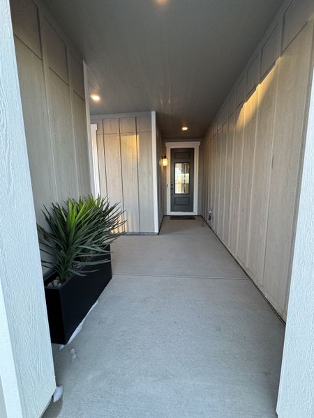 A welcoming entryway with modern paneling, soft lighting, and a potted plant.