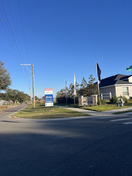Entrance to Otter Woods Estates by Highland Homes of Florida, with flags and signage in Auburndale, FL.