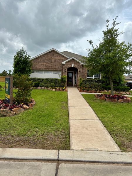 A charming brick home with a lush yard and pathway in Freeman Ranch by LGI Homes (Katy, TX).