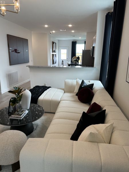 A modern living area featuring a plush white sectional sofa, sleek decor, and open concept layout with stylish accents.