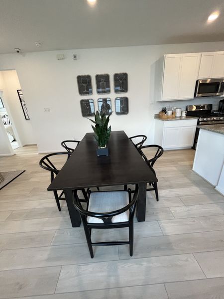 A modern dining area with a sleek black table, elegant chairs, and stylish wall decor, adjacent to a bright kitchen. A modern dining area with a sleek black table, elegant chairs, and stylish wall decor, adjacent to a bright kitchen.