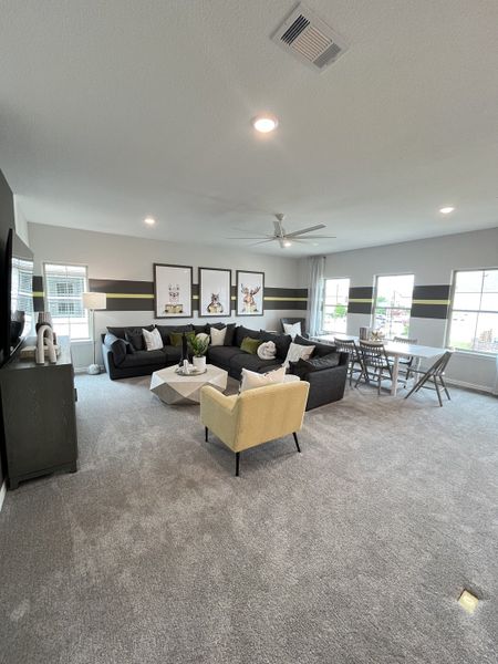 A spacious living room featuring modern décor, plush carpeting, and abundant natural light with stylish wall art.