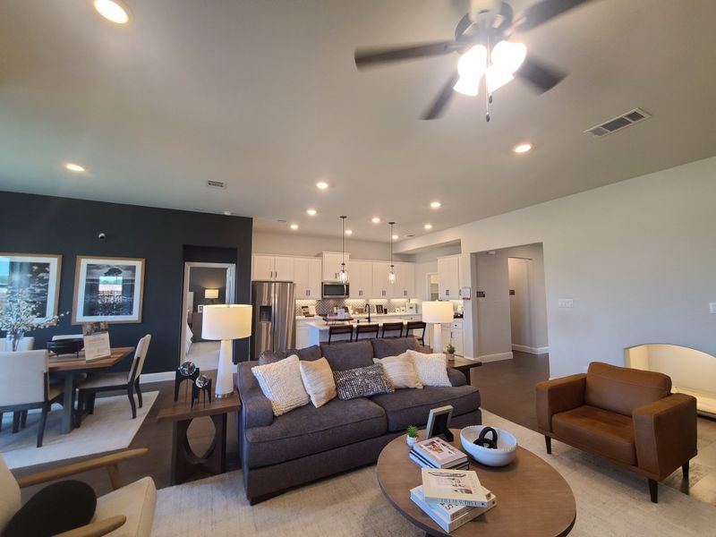 A spacious open-concept living area with cozy seating, modern kitchen, and elegant dining space, featuring warm lighting and stylish decor.